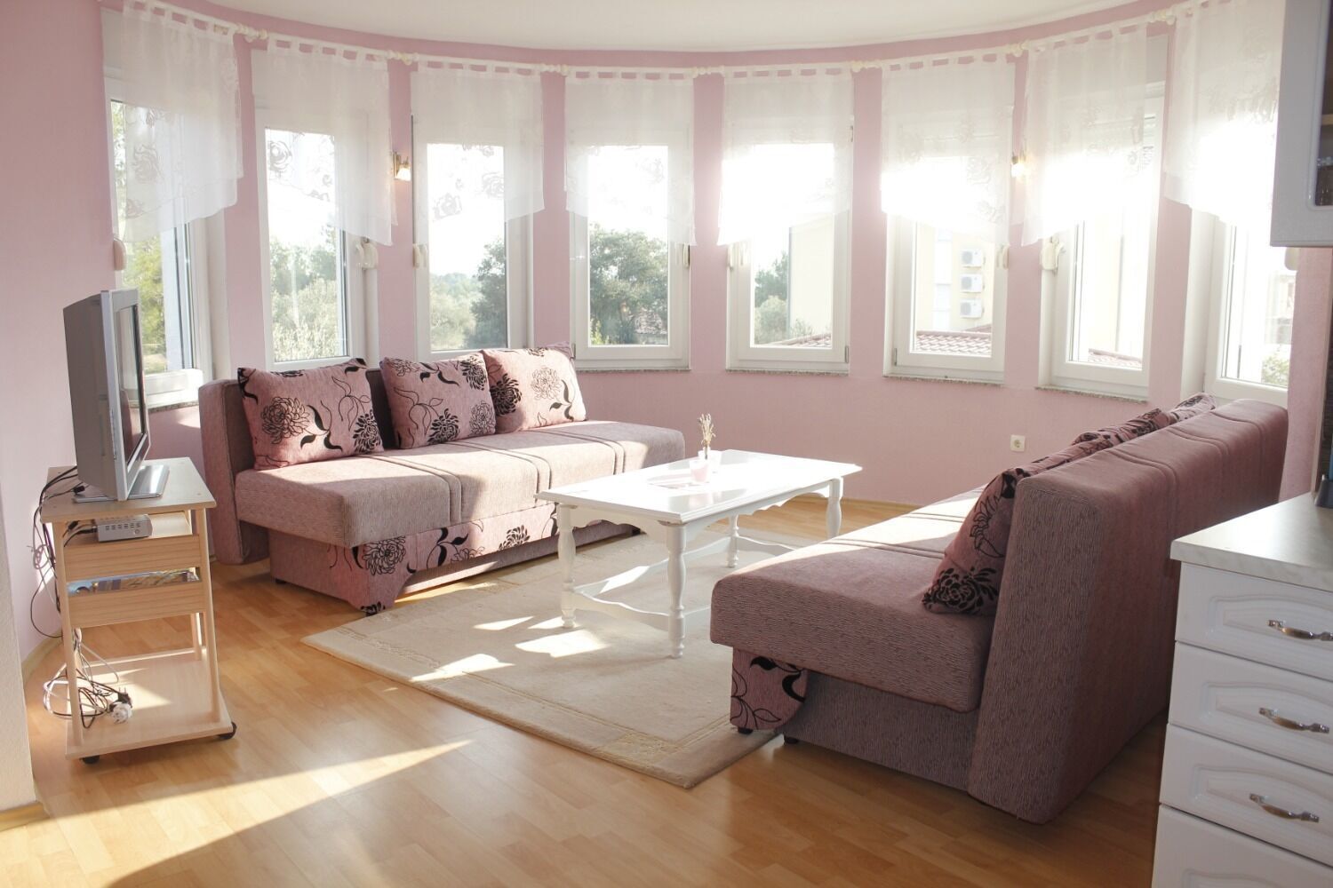 Una sala de estar acogedora con un sofá, una mesa de centro y un televisor sobre un mueble.