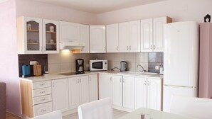A modern kitchen with white cabinets, a microwave, a coffee maker, and a sink. - Apartments Marin (Biograd na Moru)