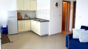 A compact kitchen with white cabinets, a built-in sink, and a refrigerator. - Apartment Blue (Mali Losinj)