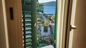 A view through a door to a balcony with a view of the sea and a stone pathway. - Apartment Blue (Mali Losinj)