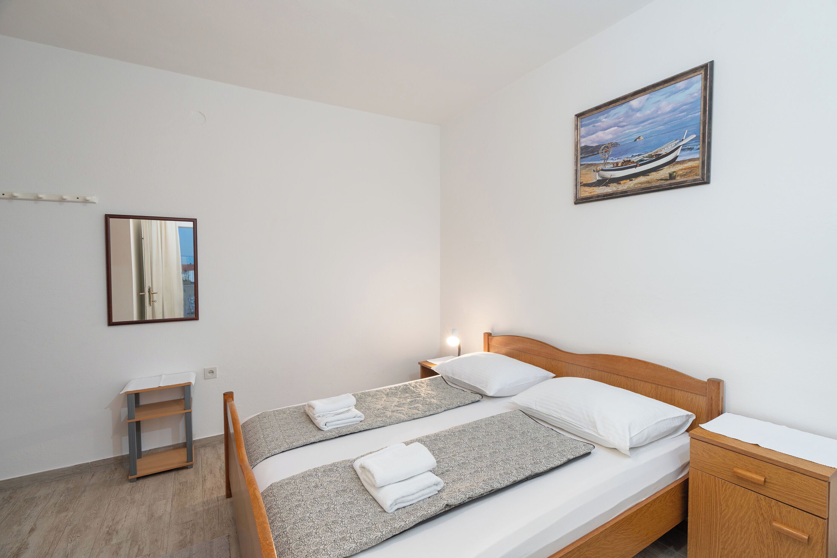 A clean, modern room with a bed, bedside table, and a painting on the wall.