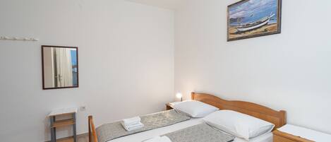 A clean, modern room with a bed, bedside table, and a painting on the wall.