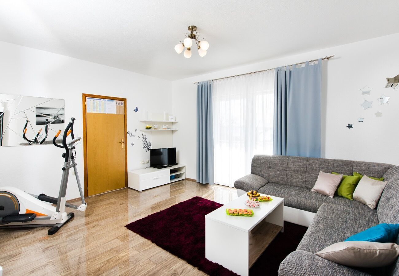 A living room with a grey sofa, a white coffee table, a red rug, a TV, and exercise equipment.