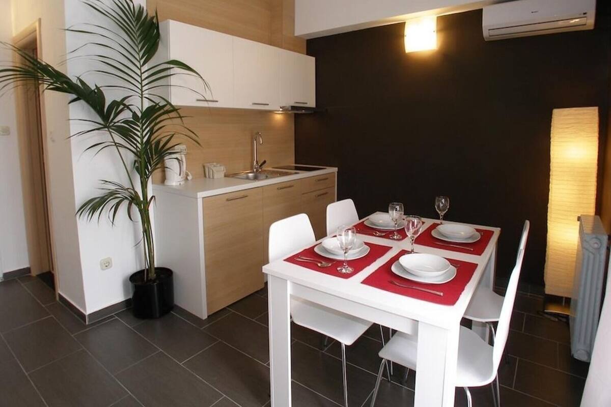 A modern kitchen with white cabinets, a central island, and a dining area with a table set for two.