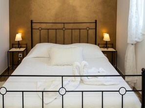A neatly made bed with a metal frame, two bedside lamps, and a plain wall behind it. - Apartment Slavena (Okrug)