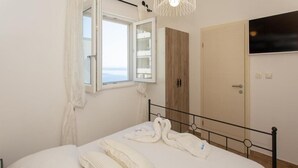 A bedroom with a bed, a window, a wardrobe, and a door. - Apartment Slavena (Okrug)