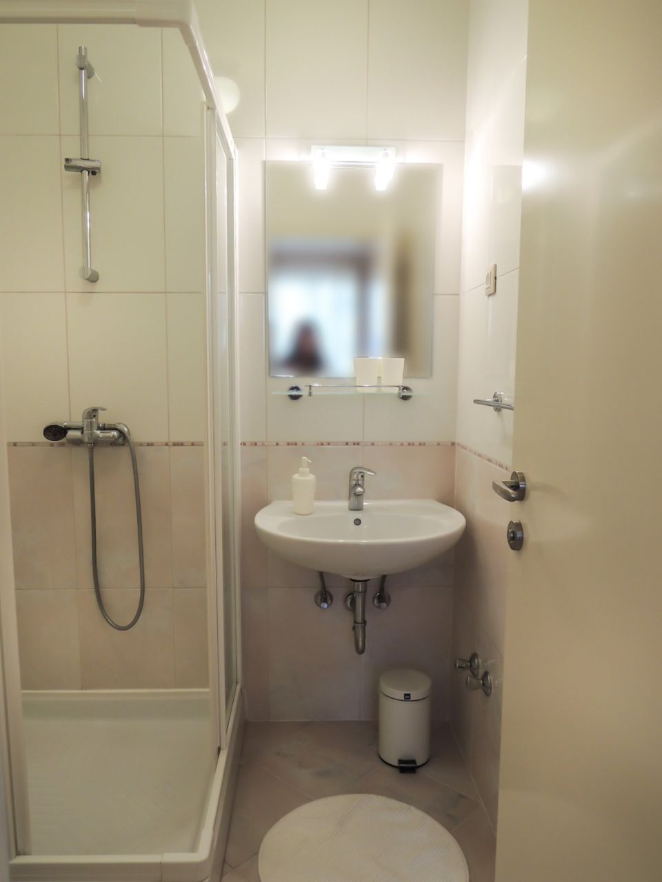 A bathroom with a shower, sink, mirror, and toilet.