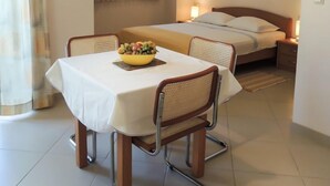 Una habitación de hotel con una cama, una mesa con frutero y una silla.