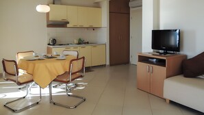 Un espacio habitable compacto con comedor, kitchenette y televisor.