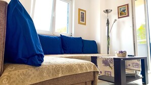 A living room with a sofa, a table, and a window with curtains. - Apartment Goran (Sali)
