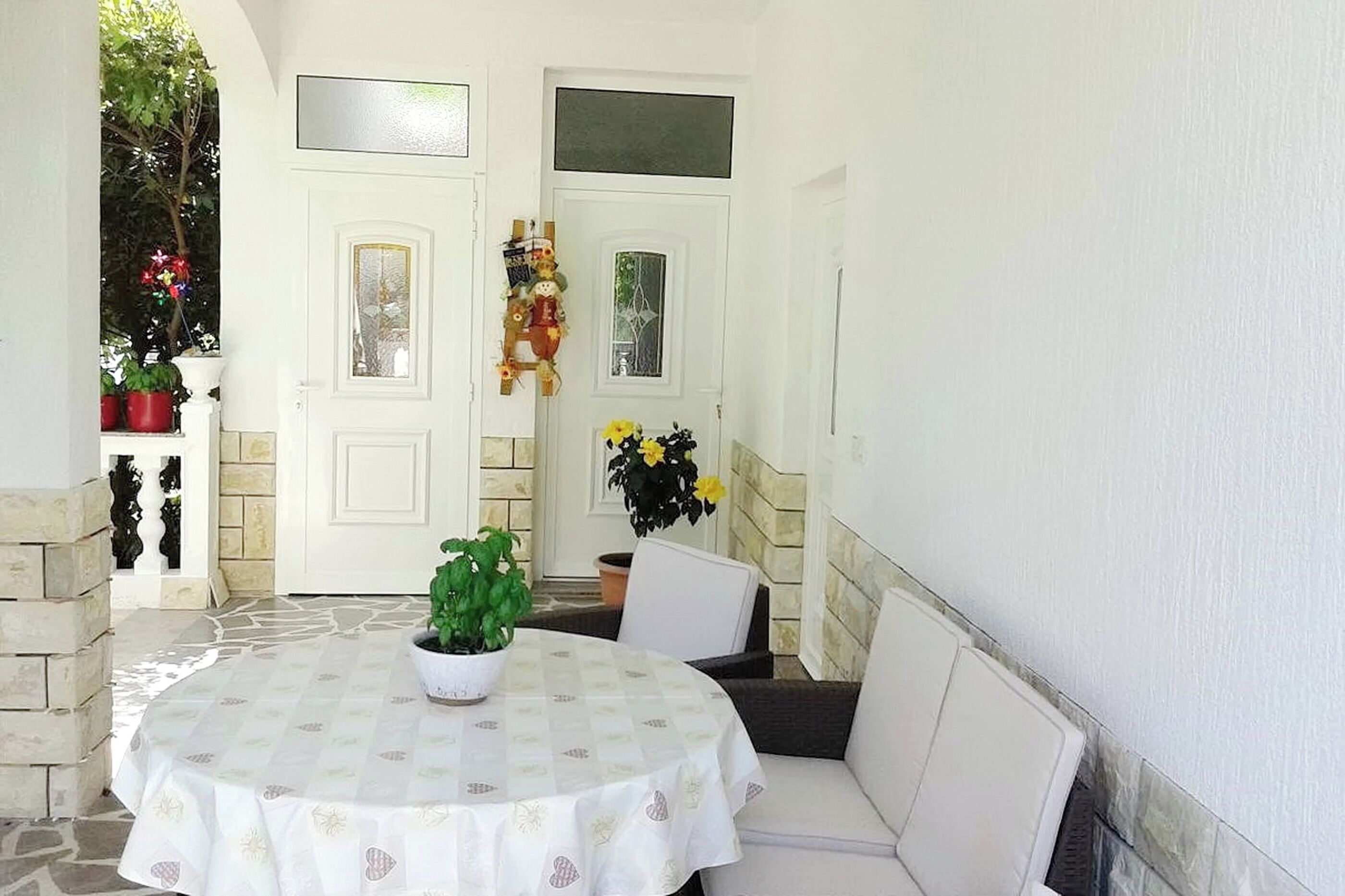 A round table with a white tablecloth, a potted plant, and a chair.