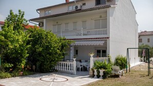 Un bâtiment à deux étages doté d’un balcon, d’un espace extérieur aménagé pour s’asseoir et d’un jardin.