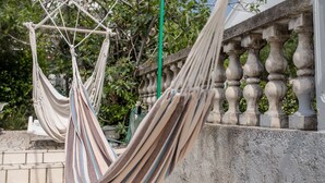 Un hamac est suspendu entre une balustrade et un mur de pierre.