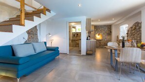 A modern living space with a blue sofa, a staircase, a kitchen, and a dining area. - House Stone (Mljet)