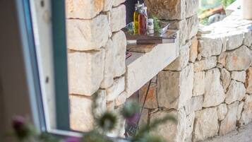 Una chimenea de piedra con un estante que sostiene botellas y una planta en maceta.