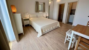 Ein Schlafzimmer mit einem Bett, Nachttischen, einer Lampe, einem Spiegel und Holzboden.