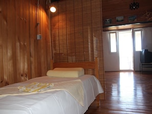 A wooden room with a bed, a wooden headboard, and a window with blinds. - Apartments Ljubo (Novalja)