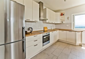 A modern kitchen with white cabinets, stainless steel appliances, and a wooden countertop. - House Brapa (Hrvace)