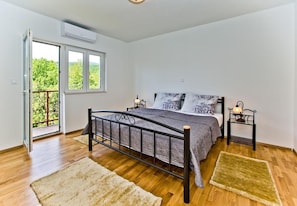 A bedroom with a bed, two bedside tables, a window, and a door leading to a balcony. - House Brapa (Hrvace)