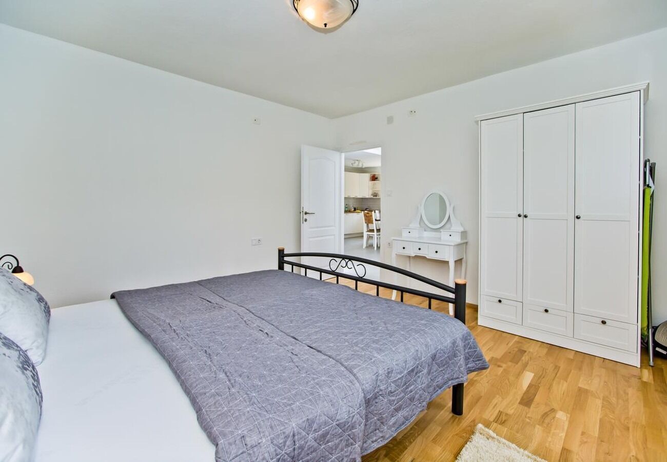 A bedroom with a bed, a wardrobe, a desk, and a mirror.