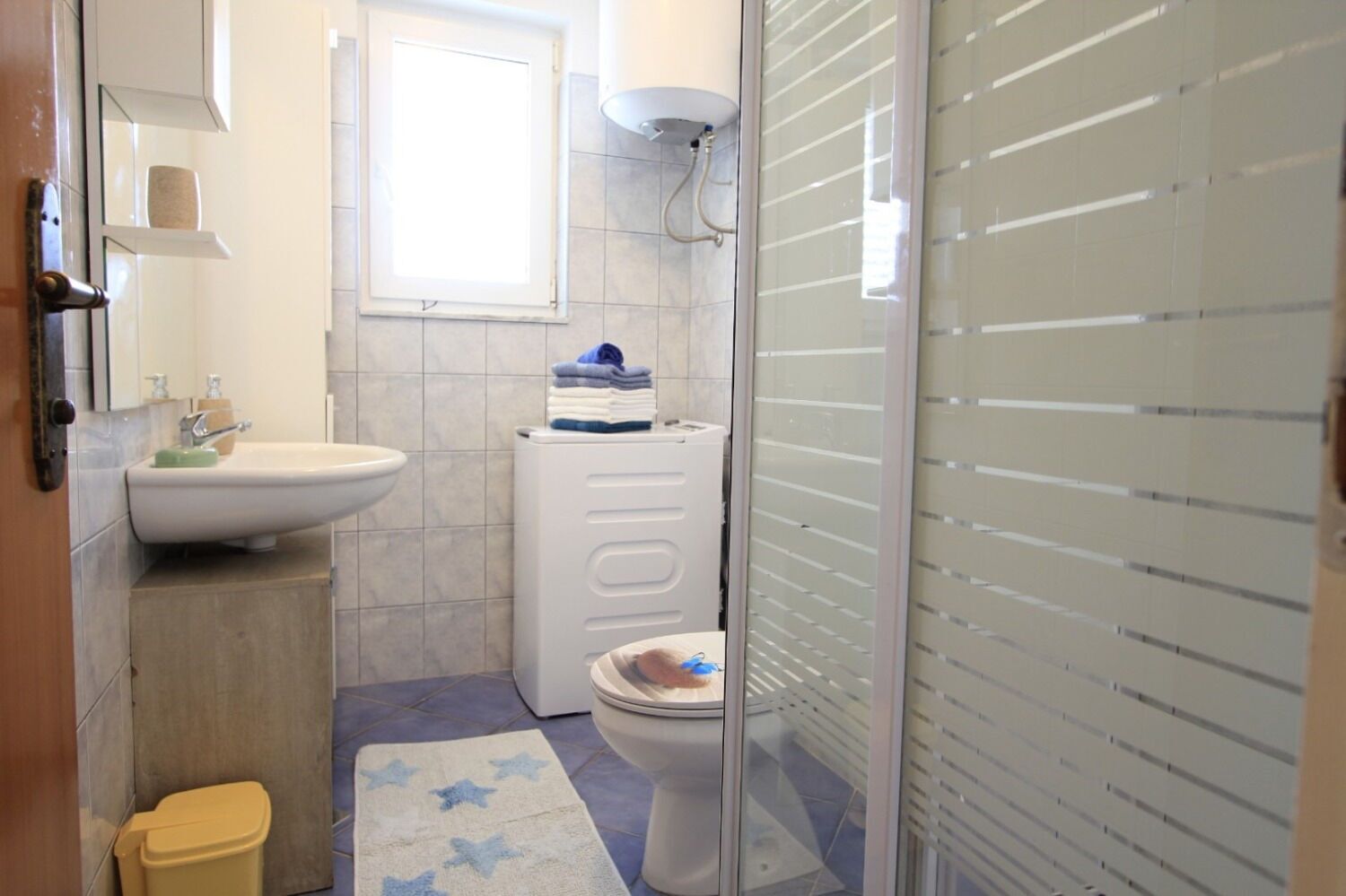 Ein kleines Badezimmer mit Waschbecken, Toilette und Duschbereich.