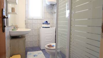 Ein kleines Badezimmer mit Waschbecken, Toilette und Duschbereich.