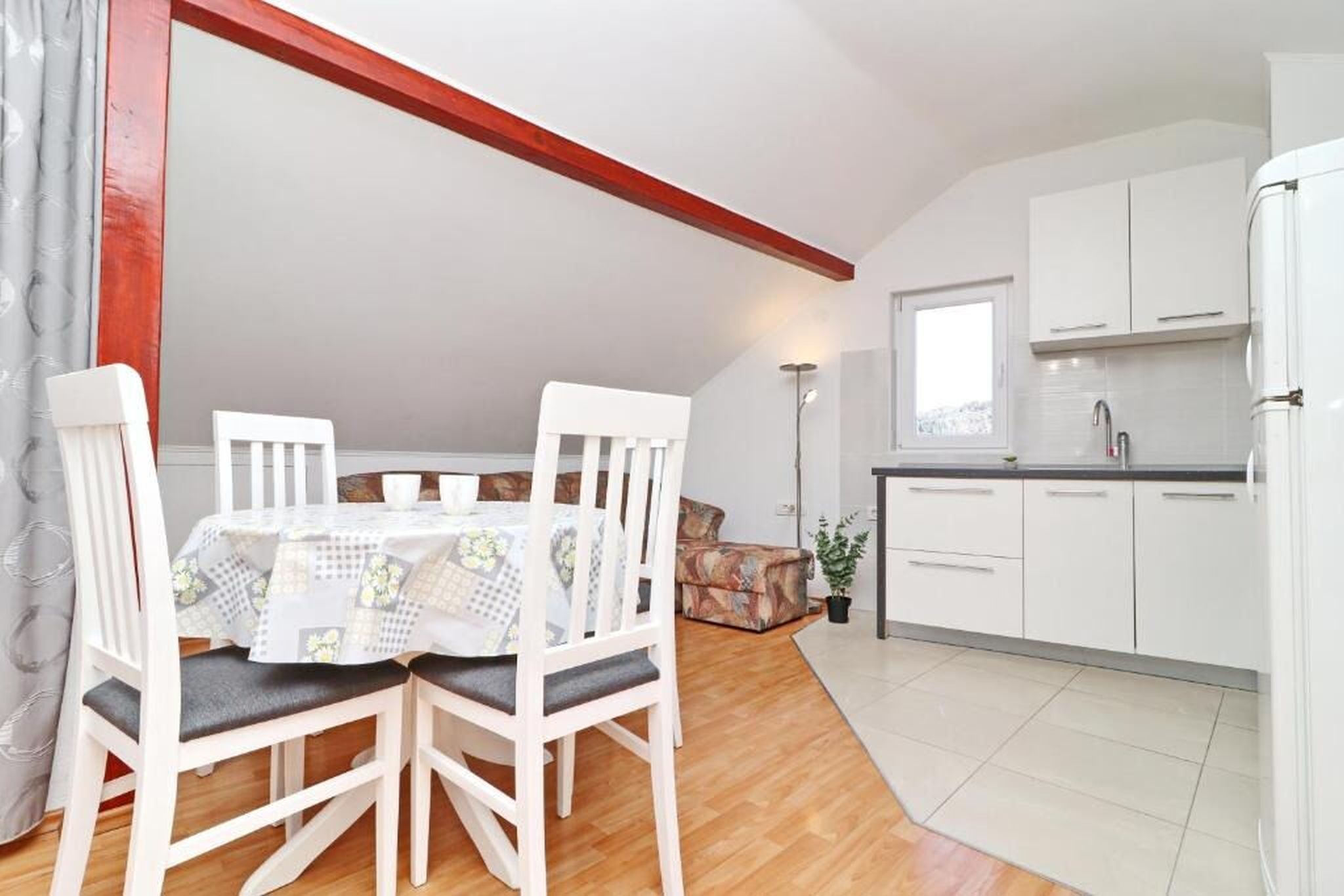 A compact kitchen with white cabinets, a white refrigerator, and a dining area with a table and chairs.