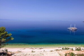 Ένα σκάφος σε μια ήρεμη θάλασσα, με καθαρό ορίζοντα και μια βραχώδη ακτογραμμή.
