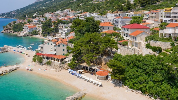 A coastal town with buildings, a beach, and clear waters. - Apartments Ivo (Omis)