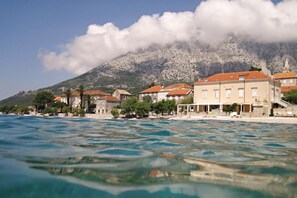 A coastal town with buildings along the waterfront, a mountain in the background, and clear blue waters. - Apartments Boris (Orebic)