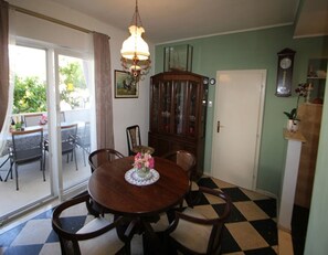 A dining room with a round table, chairs, a chandelier, and a checkered floor. - Apartments Boris (Orebic)