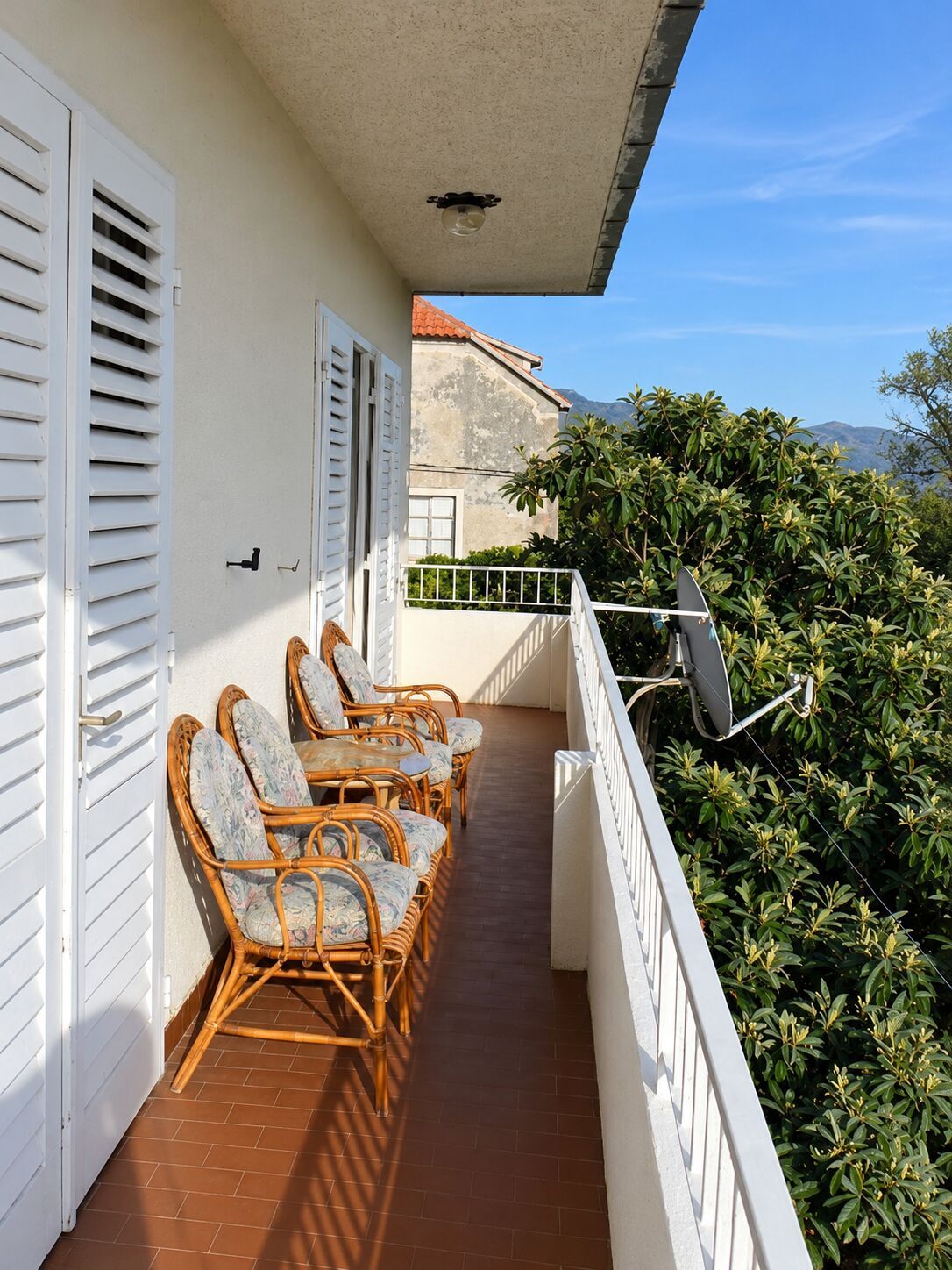 A balcony with wicker furniture and a satellite dish.