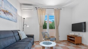 A living room with a sofa, a chair, a small table, a TV, and a window with curtains. - Apartment Uga2 (Kolan)