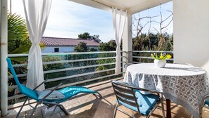 A balcony with a table and chairs, a view of a house, and a fence. - Apartments Bari (Kolan)