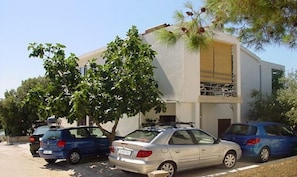 A modern building with a flat roof and a balcony. There are parked cars in front of the building. - Apartments Bari (Kolan)