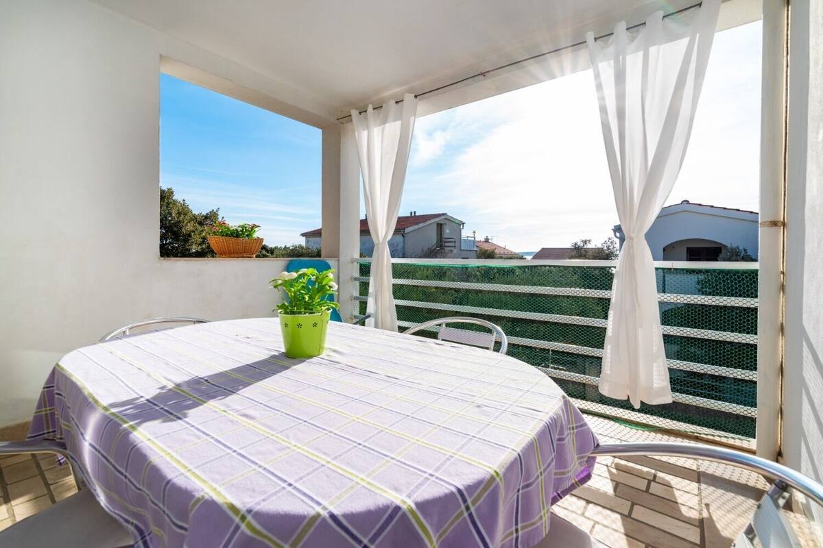 Un balcon avec une table et des chaises, une plante en pot et une vue sur les bâtiments.