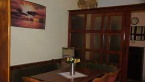A dining area with a wooden table, green cushioned benches, and a vase with flowers. - Apartments Sonja (Podgora)