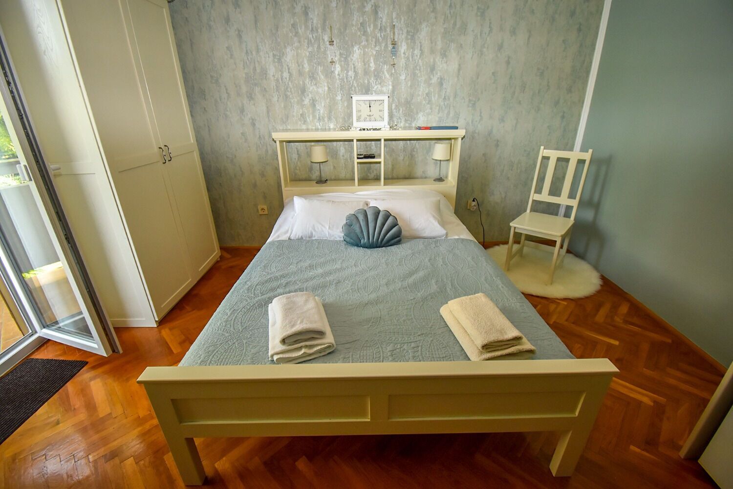 Een slaapkamer met een bed, nachtkastjes, een stoel en een kledingkast.