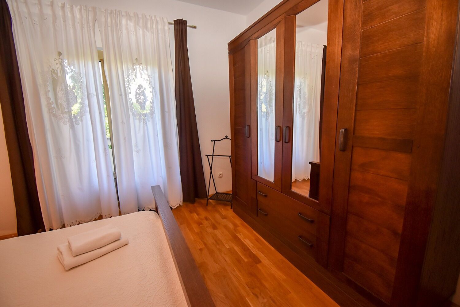 Une chambre à coucher avec un lit, une armoire en bois et des rideaux.