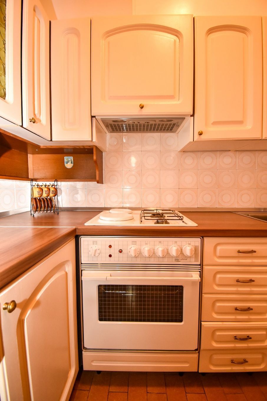 Une cuisine avec des meubles blancs, une cuisinière et un dosseret carrelé.