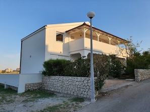 A modern white building with a stone wall and a lamp post. - Apartments Rising Sun (Vir)
