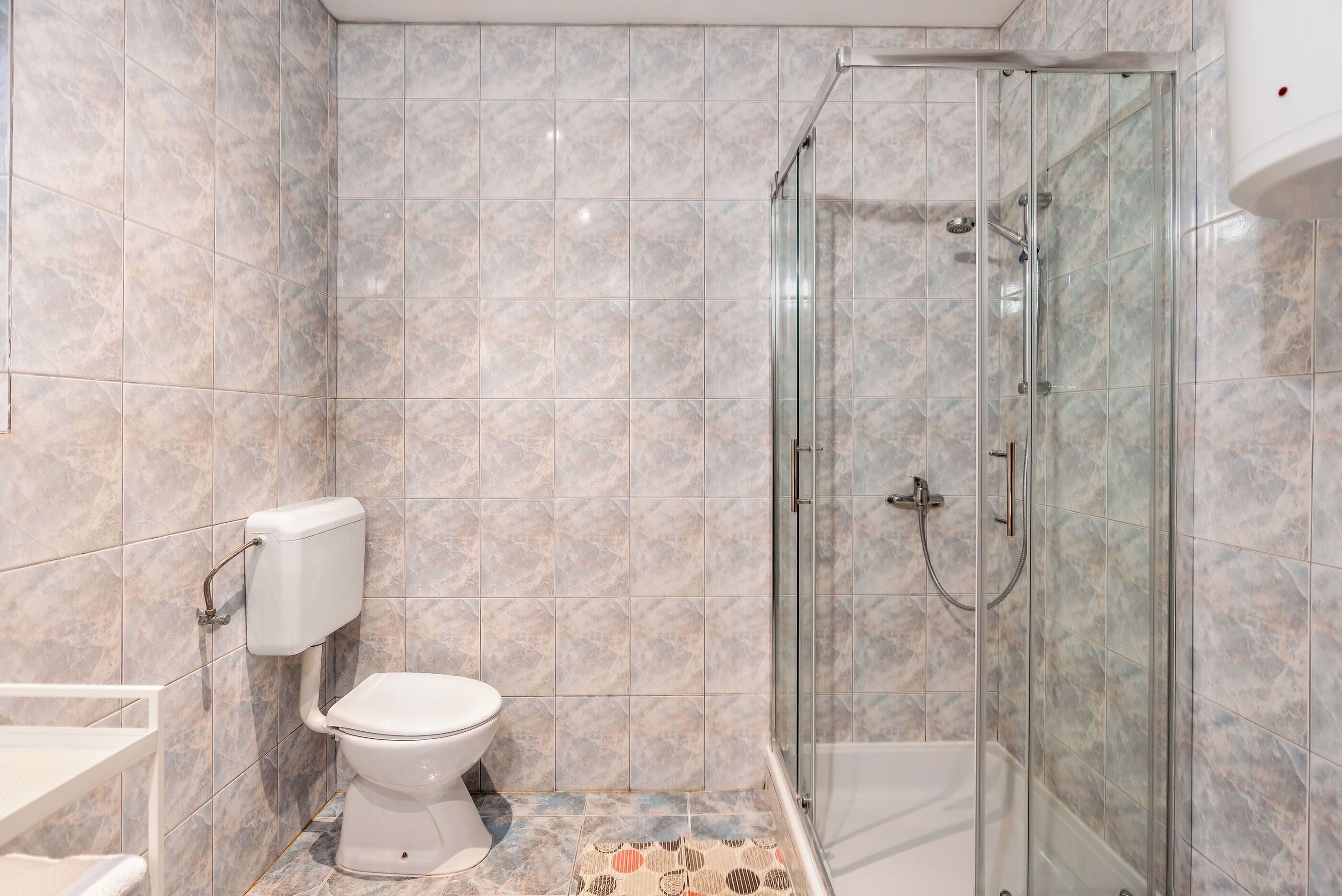 A bathroom with a toilet, shower, and glass-enclosed shower stall.