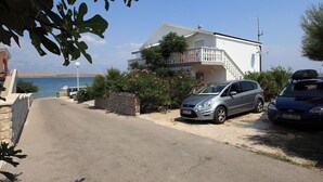 Una propiedad costera con un edificio blanco, un balcón y un coche estacionado en la entrada.