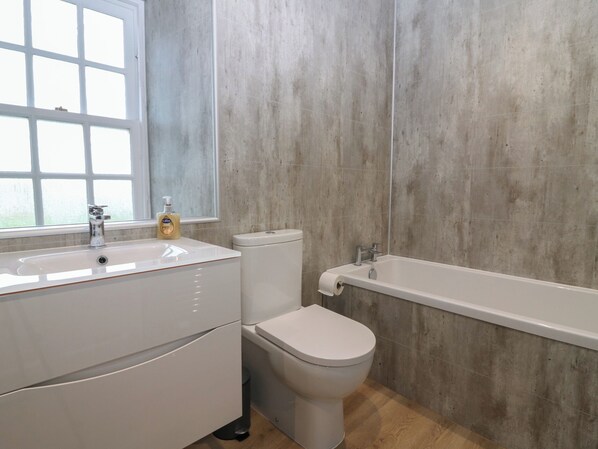 Une salle de bain avec un lavabo, des toilettes et une baignoire, le tout de couleur blanche.