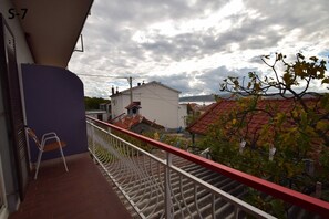 A balcony with a metal railing, a chair, and a view of houses and trees. - Apartments and Rooms Mirja (Starigrad)