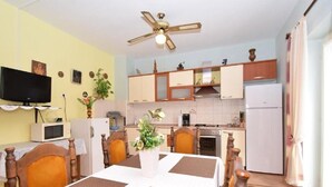 Cocina compacta con comedor, que incluye ventilador de techo, televisor y microondas.