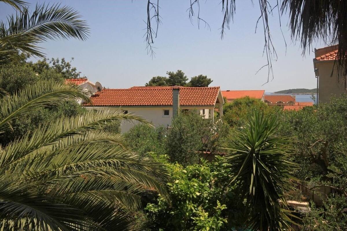 A building with a red-tiled roof surrounded by lush greenery and palm trees.