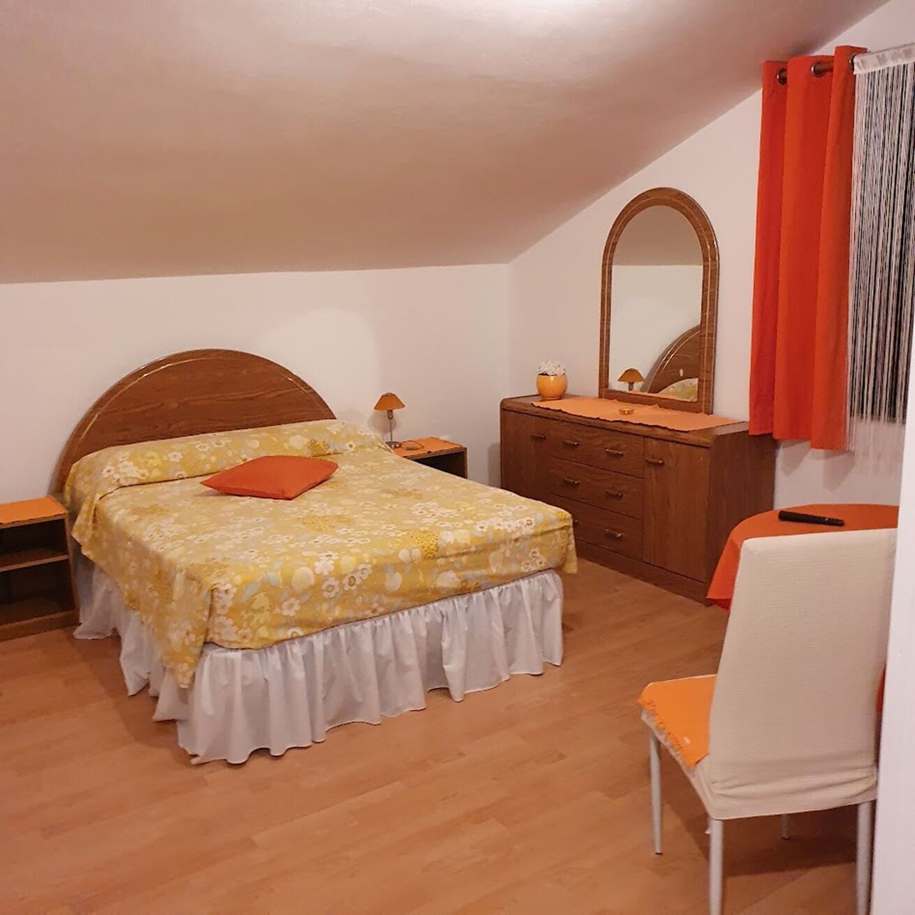 A bedroom with a wooden bed, a nightstand, a dresser, and a chair.