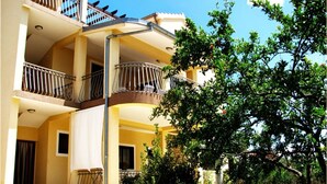 A multi-story building with balconies, a courtyard, and a tree. - Apartment Ivica (Tribunj)
