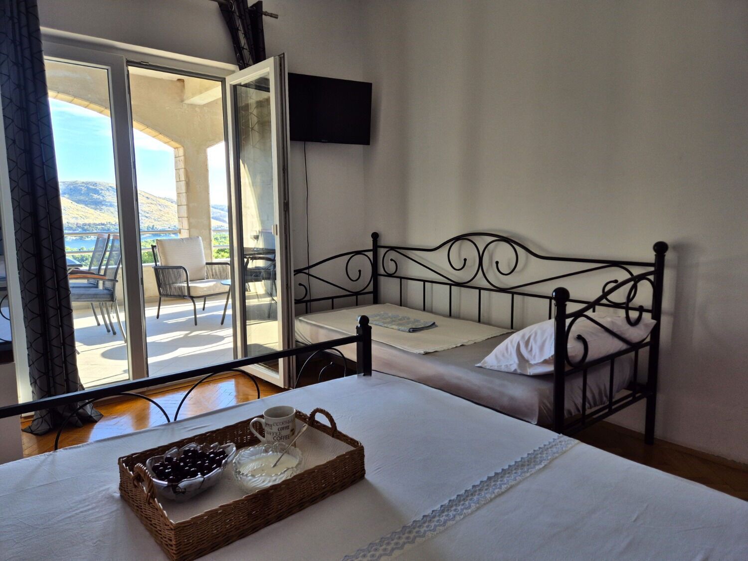A bedroom with a bed, a TV, and a balcony with chairs and a table.